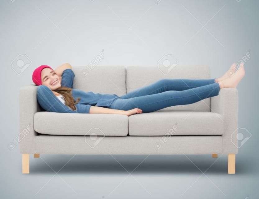 concetto di casa, tempo libero e felicità - sorridente ragazza sdraiata sul divano