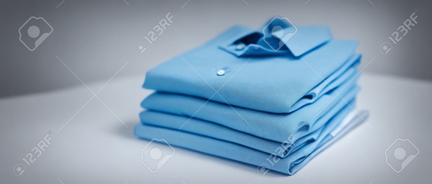 repassage, blanchisserie, vêtements, entretien ménager et objets notion - close up de chemises repassés et pliés sur la table à la maison