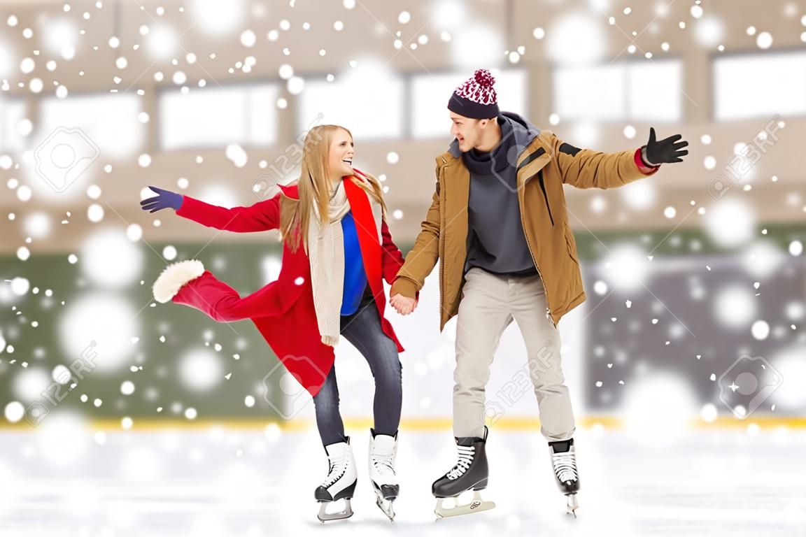 les gens, l'amitié, le sport et le concept de loisirs - heureux couple se tenant les mains sur la patinoire
