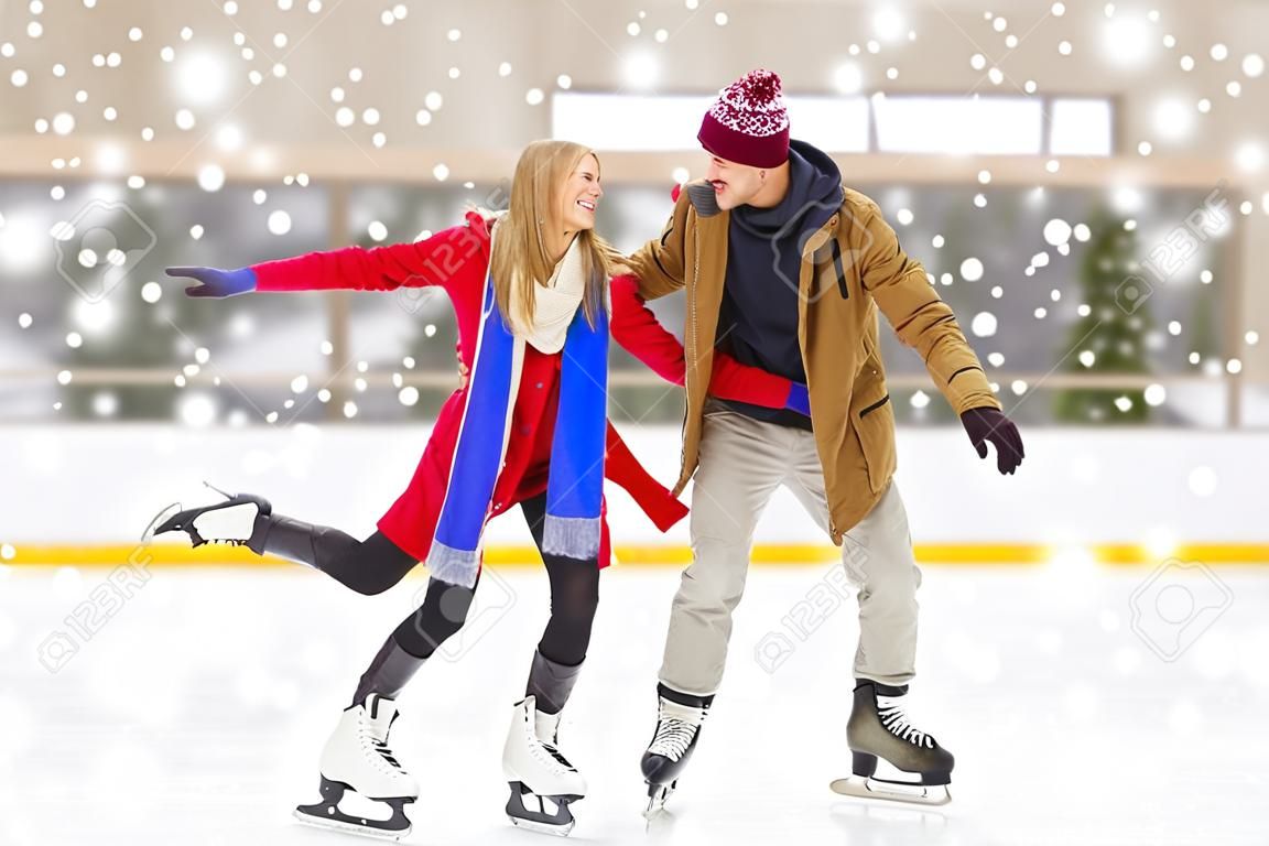 persone, l'amicizia, lo sport e il tempo libero concept - felice coppia per mano sulla pista di pattinaggio
