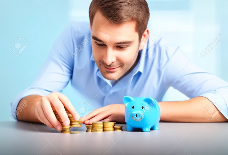 negocios, personas, finanzas y dinero concepto de ahorro - hombre de negocios con la hucha y monedas en la oficina