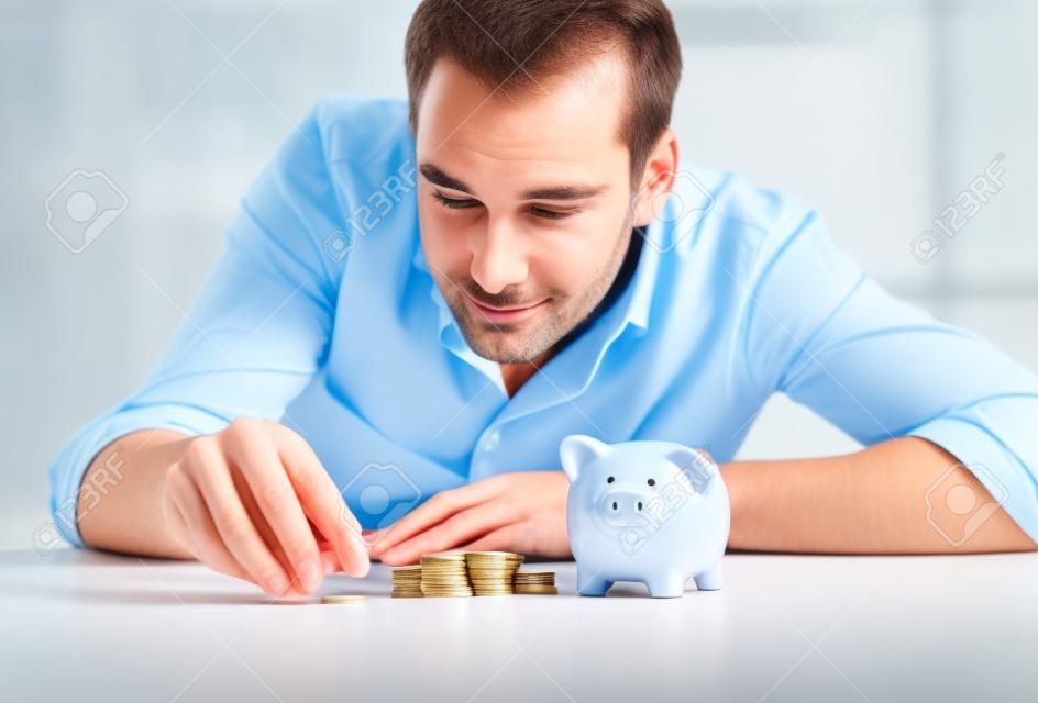 Wirtschaft, Menschen, Finanzen und Geld sparen Konzept - Geschäftsmann mit Sparschwein und Münzen im Büro