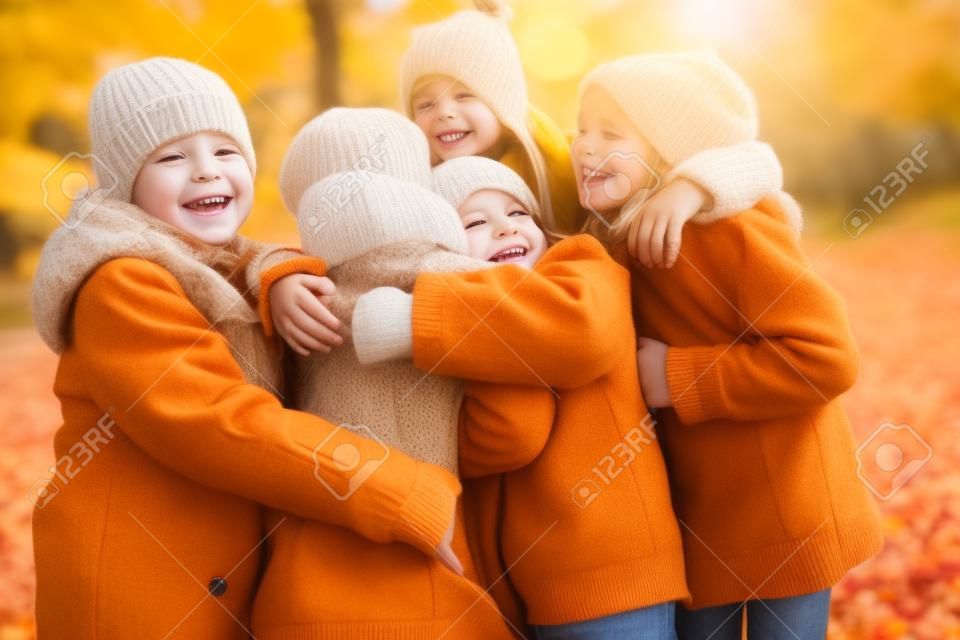 gyermekkor, szabadidő, a barátság és az emberek fogalma - csoport vidám gyerekek átölelve az őszi parkban