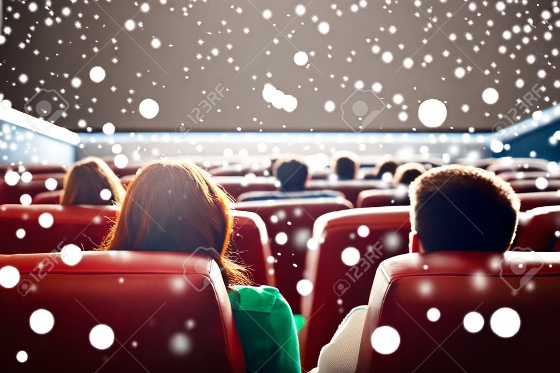 映画館、娯楽、レジャー、人々 コンセプト - 雪片を後ろから映画館で映画を見てカップル