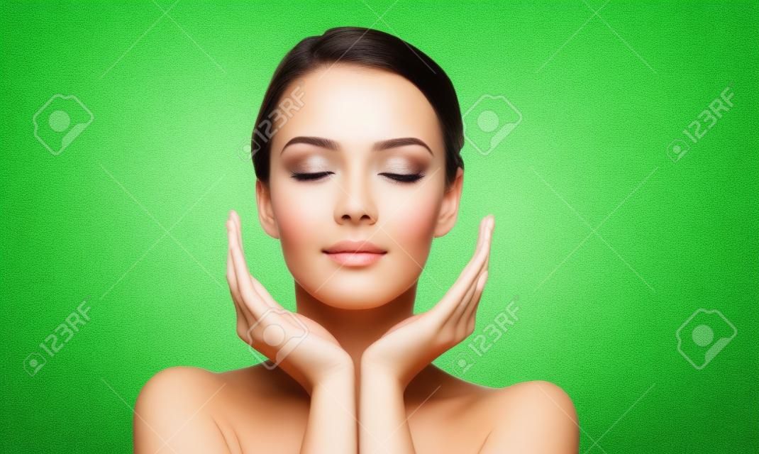 美容护肤和健康概念-年轻女性脸和手的绿色自然背景