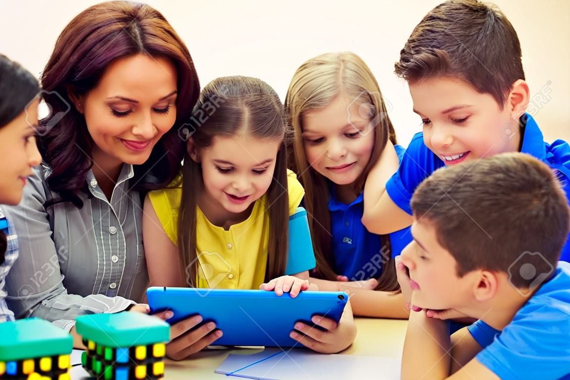 oktatás, általános iskola, a tanulás, a technológia és az emberek fogalma - csoport iskolás gyerek a tanár keres tablet pc számítógép az osztálytermi