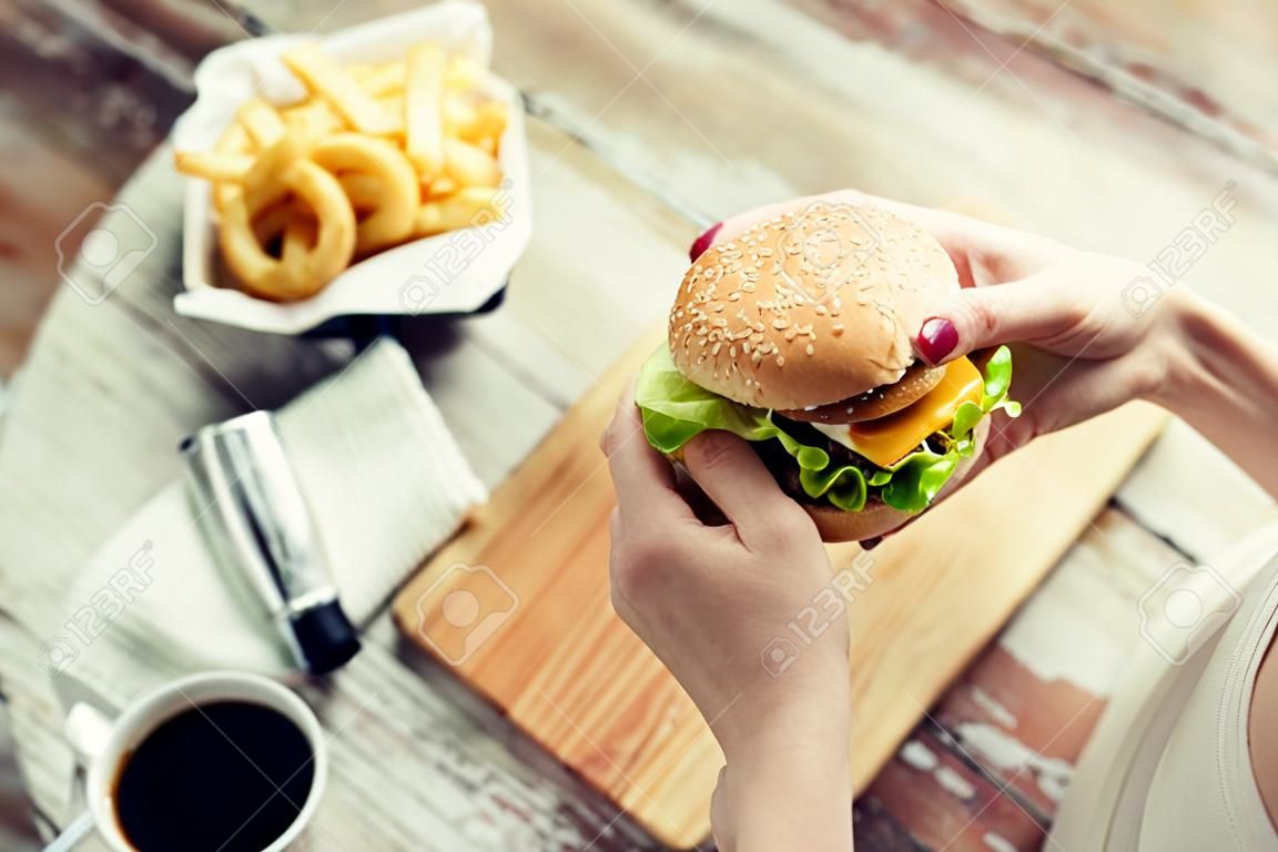 close up of woman hands holding hamburger or cheeseburger