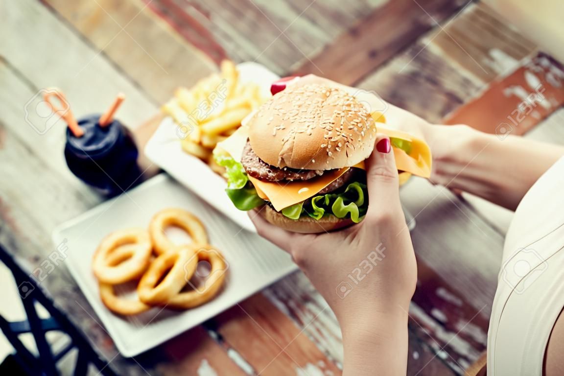 close up of woman hands holding hamburger or cheeseburger