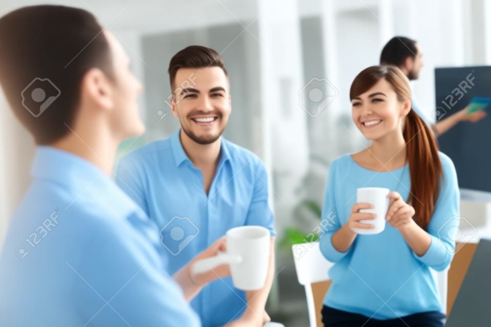 negocio, puesta en marcha y el concepto de la gente - feliz equipo creativo o estudiantes que beben el café y hablando en la oficina