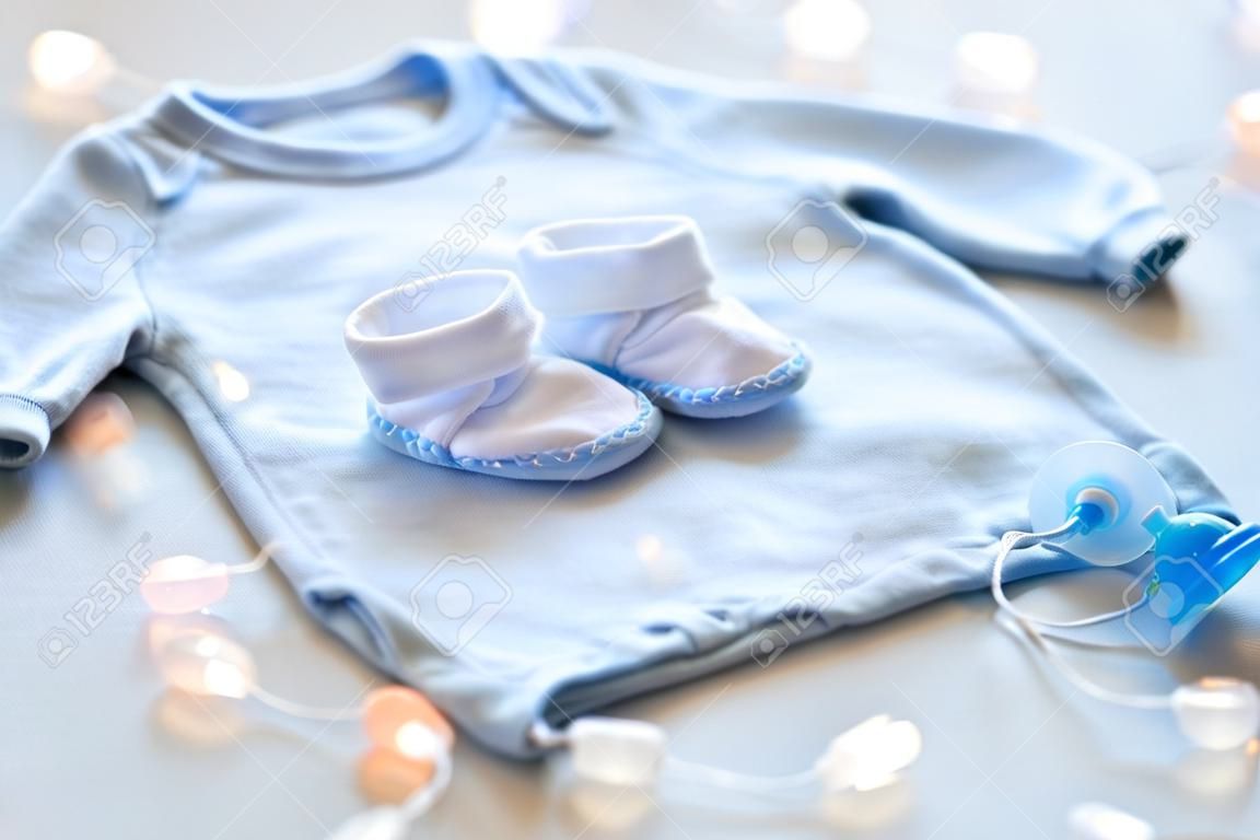 아기 옷, 유아기, 어머니와 객체의 개념 - 가까운 테이블에 신생아 소년 흰색 바디 슈트, 아기 양말과 노리개의 최대
