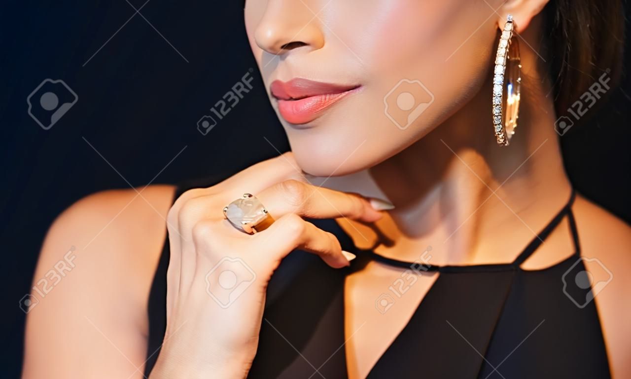 la gente, di lusso, gioielli e concetto di moda - bella donna in nero indossando orecchini di diamanti e l'anello su sfondo scuro