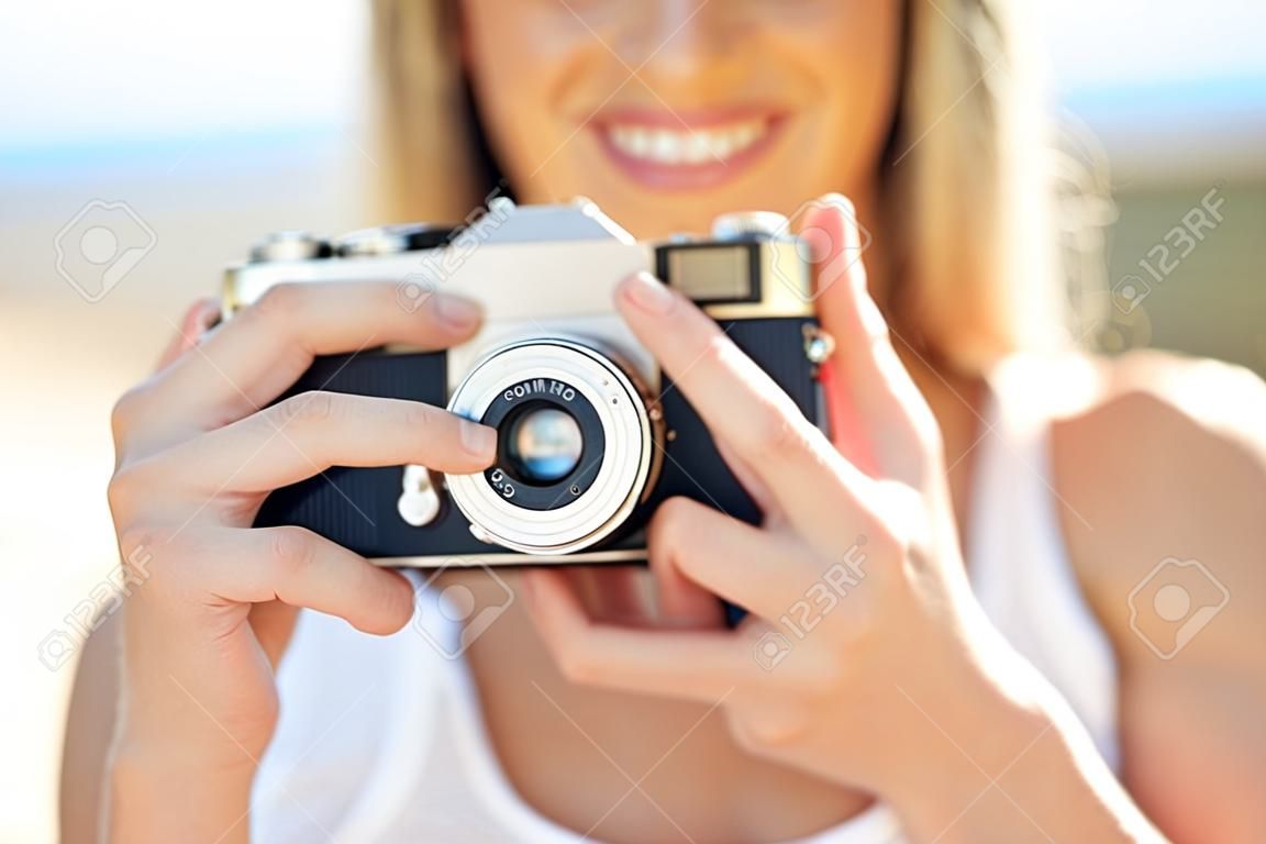 Koncepcja fotografii, wakacji letnich, wakacji i ludzi - zbliżenie młodej kobiety robiącej zdjęcie z kamerą filmową na zewnątrz