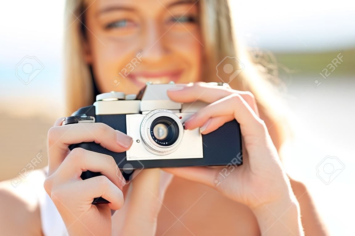 Koncepcja fotografii, wakacji letnich, wakacji i ludzi - zbliżenie młodej kobiety robiącej zdjęcie z kamerą filmową na zewnątrz