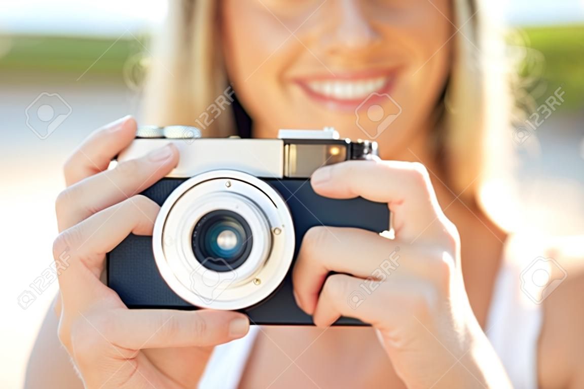 photography, summer holidays, vacation and people concept - close up of young woman taking picture with film camera outdoors