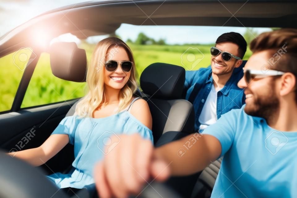 lazer, viagem de estrada, viagens e conceito de pessoas - amigos felizes dirigindo em carro cabriolet ao longo da estrada do país