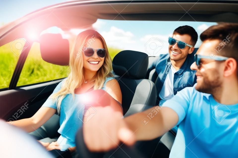 vrijetijdsbesteding, road trip, reizen en mensen concept - gelukkige vrienden rijden in cabriolet auto langs country road