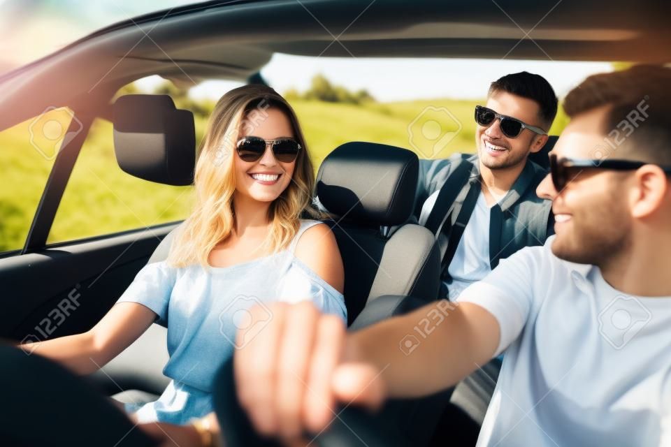 lazer, viagem de estrada, viagens e conceito de pessoas - amigos felizes dirigindo em carro cabriolet ao longo da estrada do país