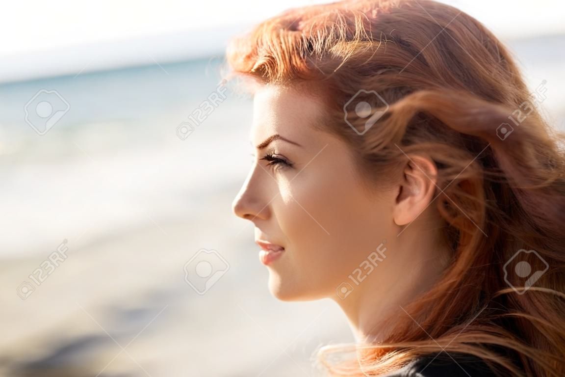 人，面部表情和情感概念 - 快樂年輕的紅發女人在海灘上的臉