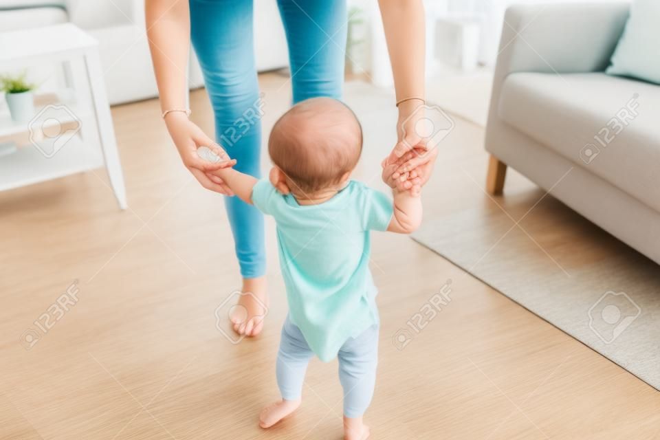 familia, niñez y el concepto de la paternidad - aprendizaje feliz pequeño bebé a caminar con la ayuda madre en el hogar