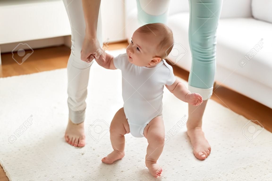 familia, niñez y el concepto de la paternidad - aprendizaje feliz pequeño bebé a caminar con la ayuda madre en el hogar