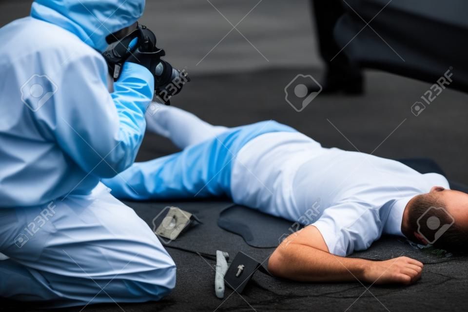 criminalist photographing dead body at crime scene