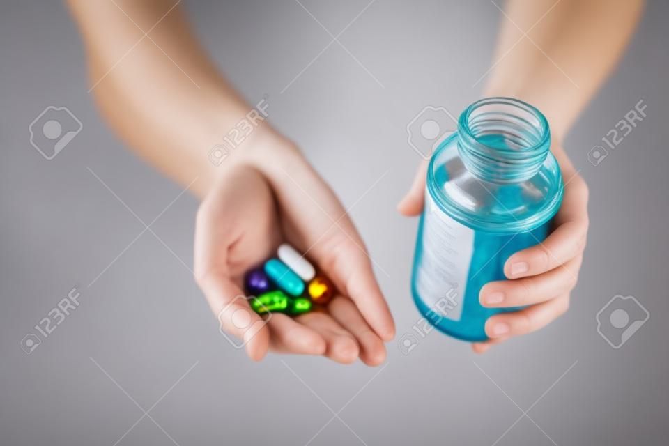 close up of hands holding medicine pills and jar