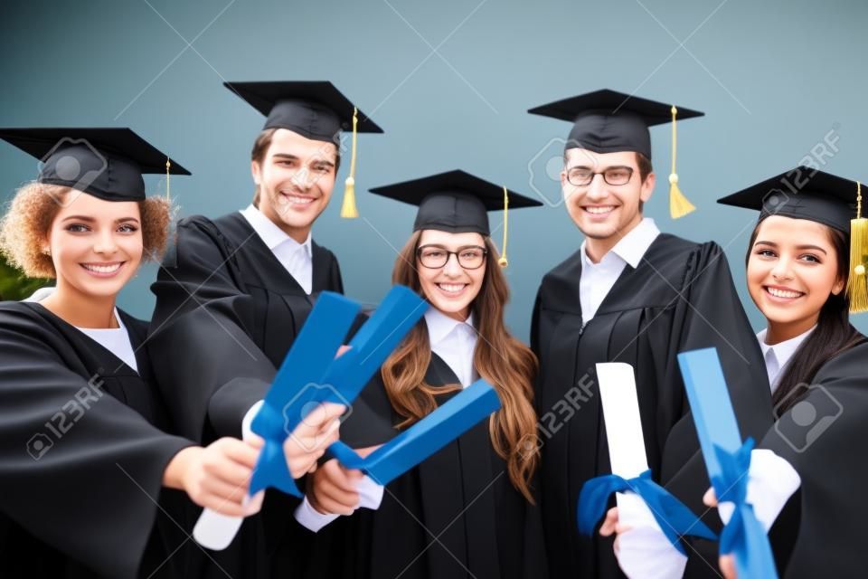 glückliche Schüler in Mörteltafeln mit Diplomen