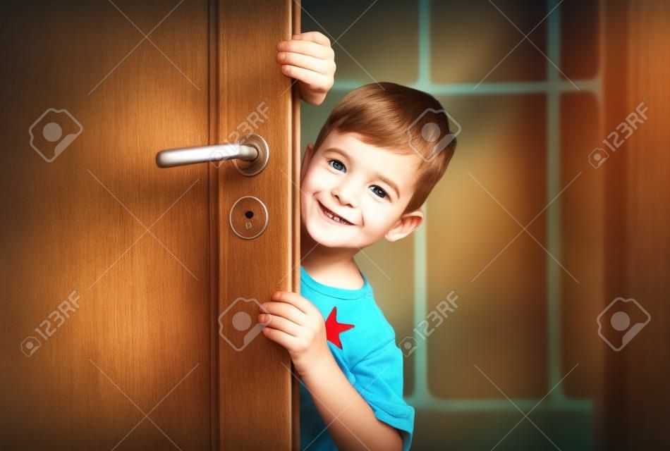 childhood, fun and people concept - happy little boy behind door at home