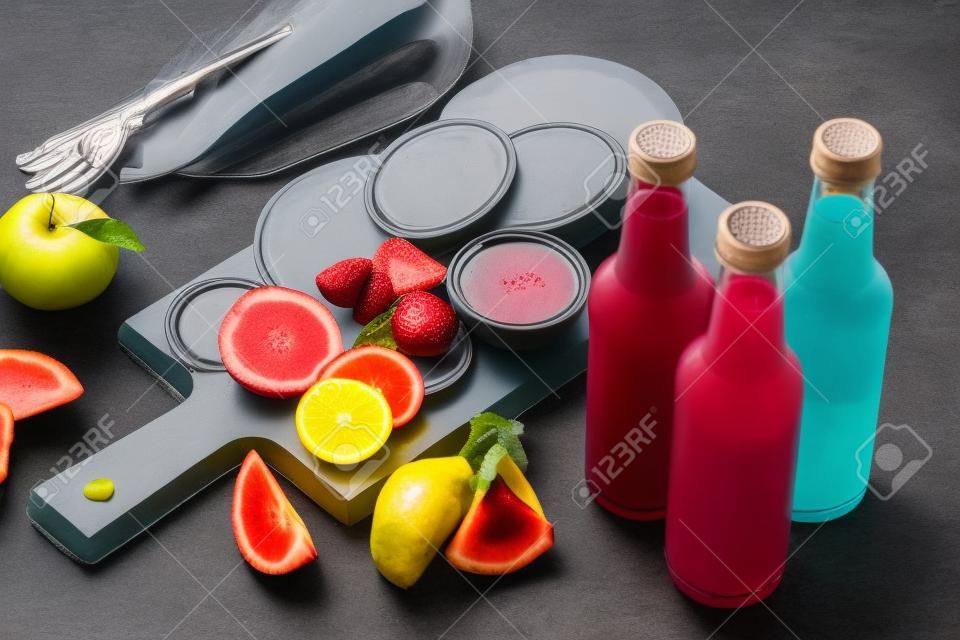 Glass bottles of fruit juice on slate table top