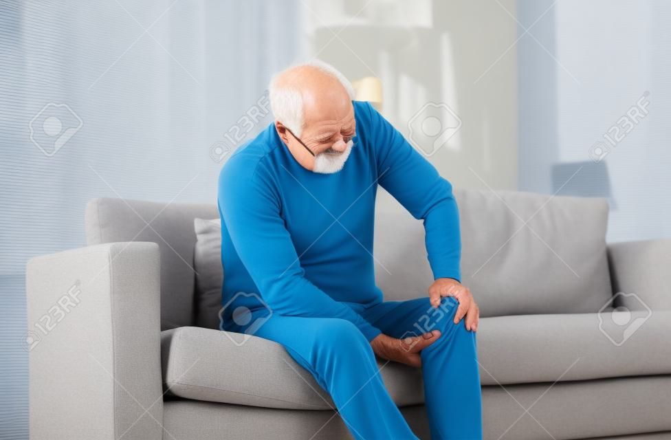 uomo anziano che soffre di dolore al ginocchio a casa