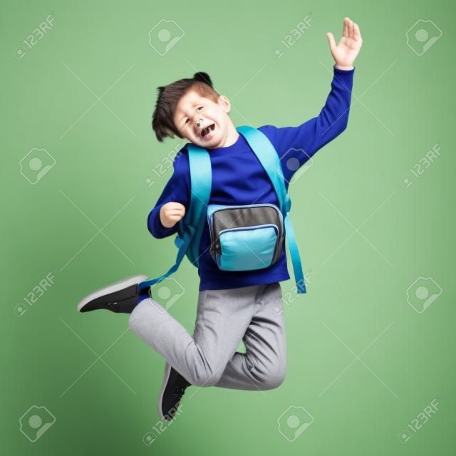 happy smiling student boy with school bag jumping