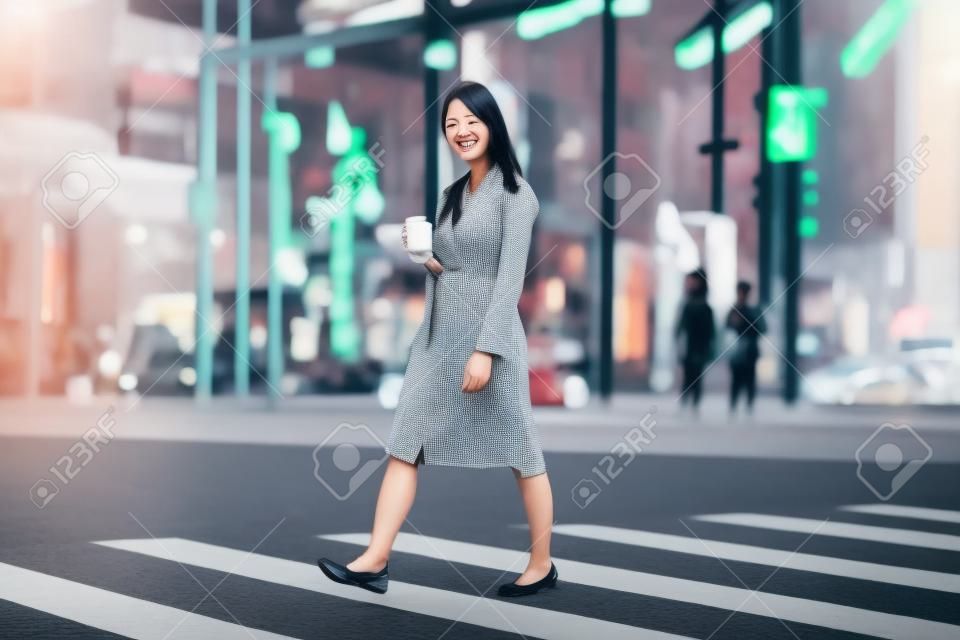 asian woman with takeaway coffee cup in city