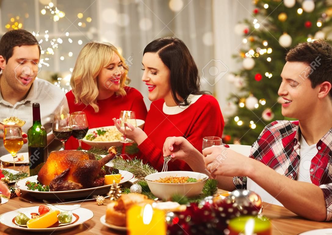 holidays and celebration concept - happy friends having christmas dinner at home and eating food