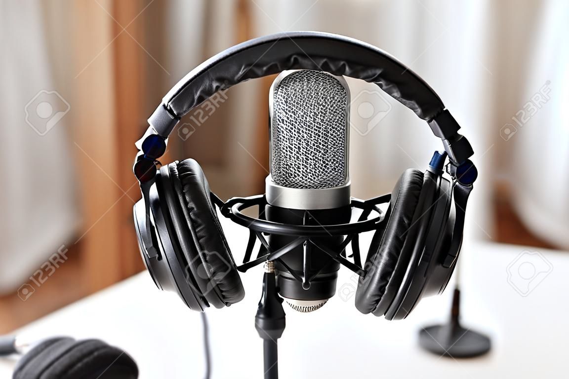 technology and audio equipment concept - headphones and microphone at home office or recording studio