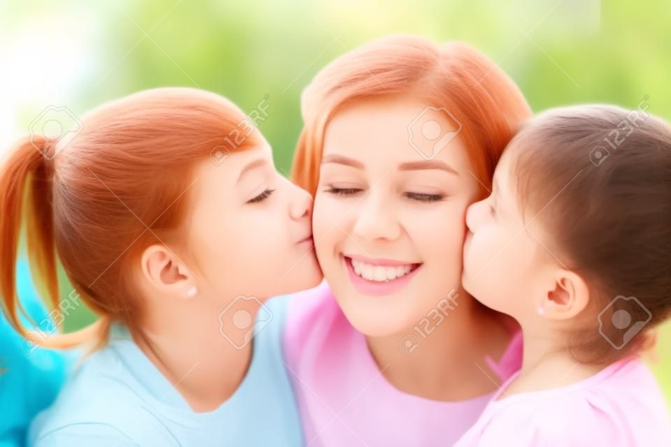 happy mother and two daughters kissing her at home