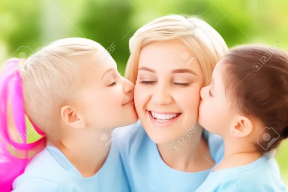 happy mother and two daughters kissing her at home