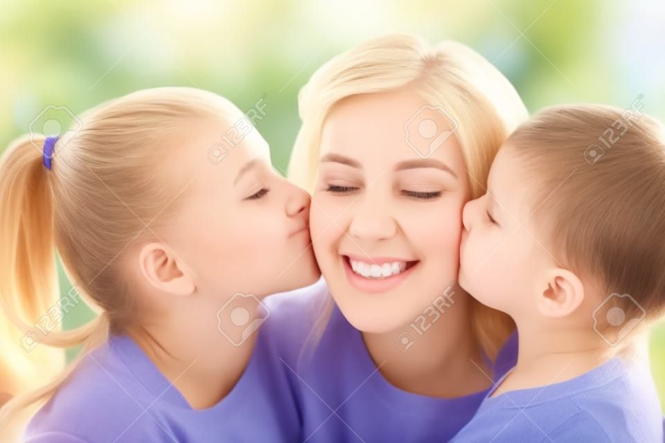 mãe feliz e duas filhas beijando-a em casa