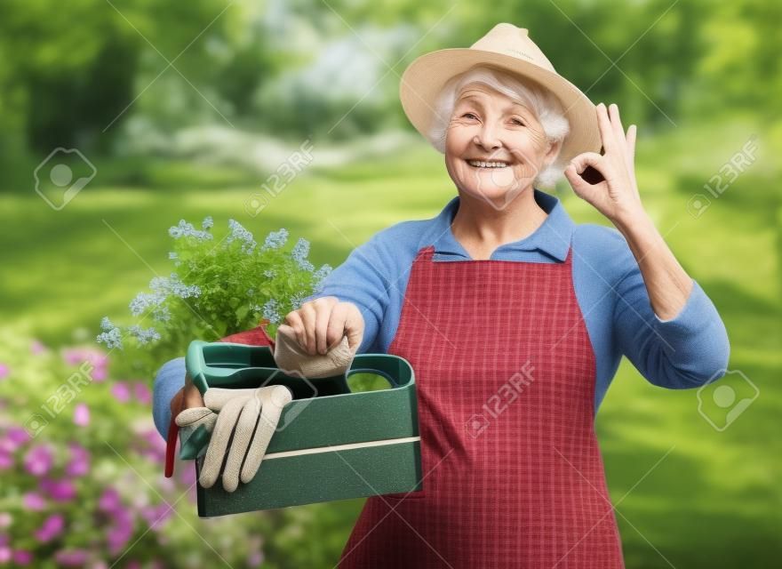 Stara kobieta z ogrodowymi narzędziami w pudełku pokazuje ok