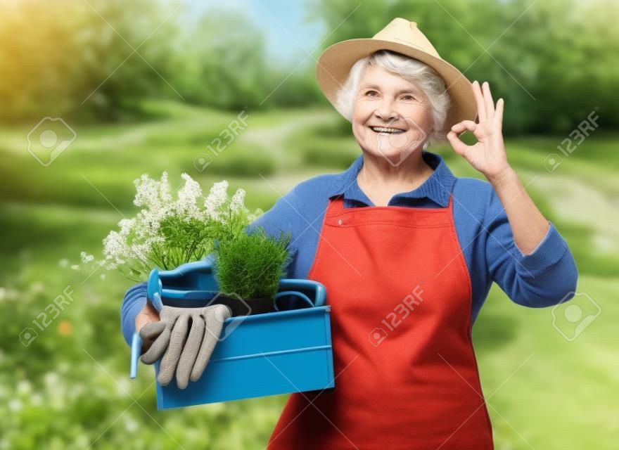 old woman with garden tools in box showing ok