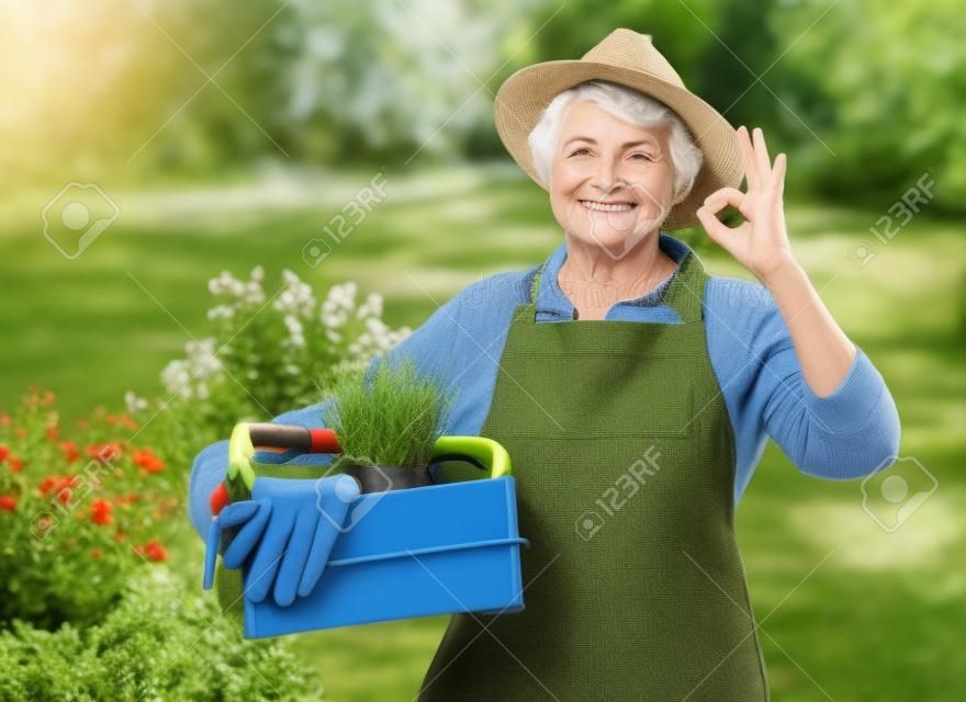 anziana con attrezzi da giardino in scatola che mostra ok