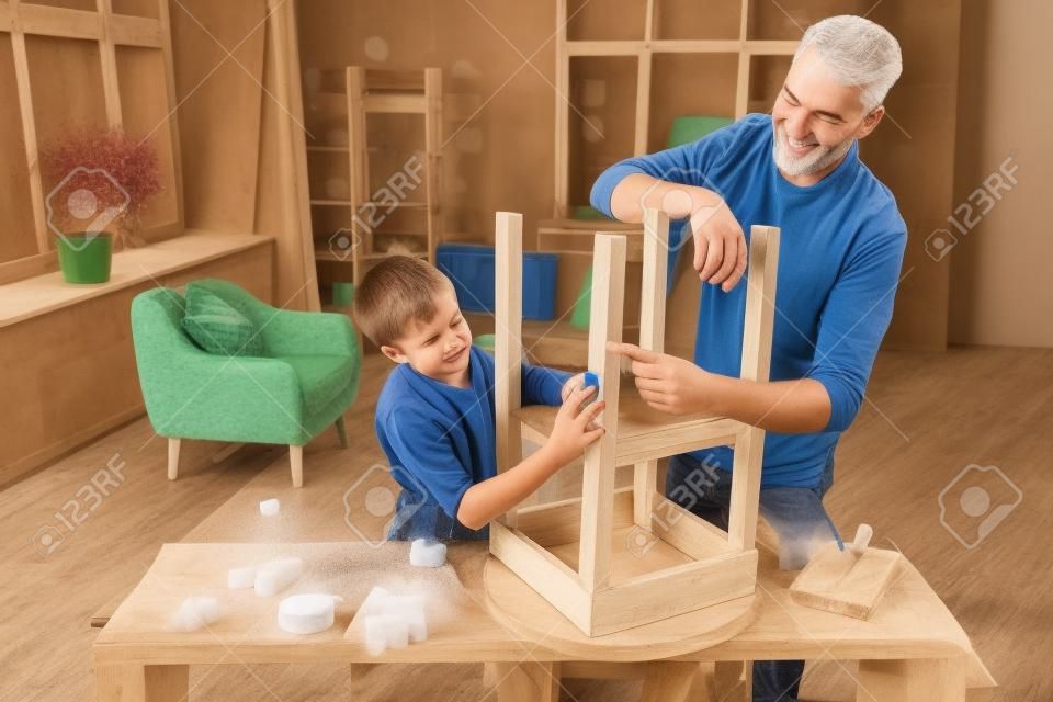 father and son sanding old table with sponge