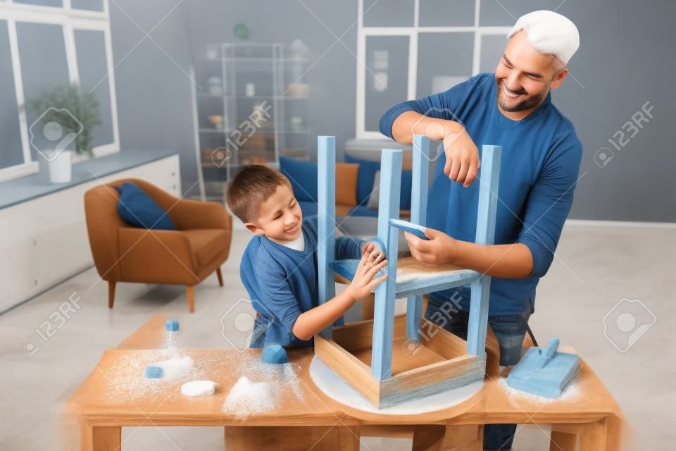 Père et fils ponçant une vieille table avec une éponge