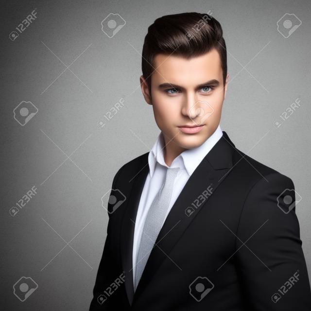 Fashion young businessman black suit casual  poses at studio