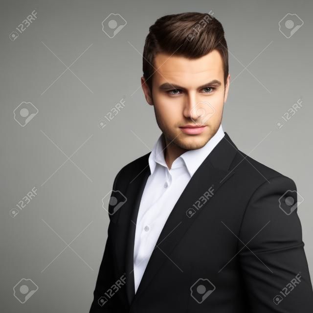 Fashion young businessman black suit casual  poses at studio