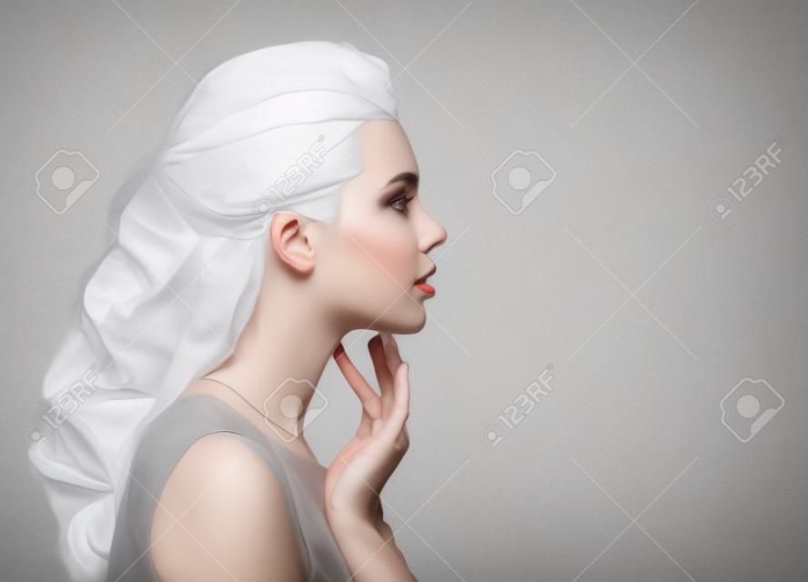 손가락으로 목을 만지는 아름다운 여성의 초상화 - 흰색으로 격리
