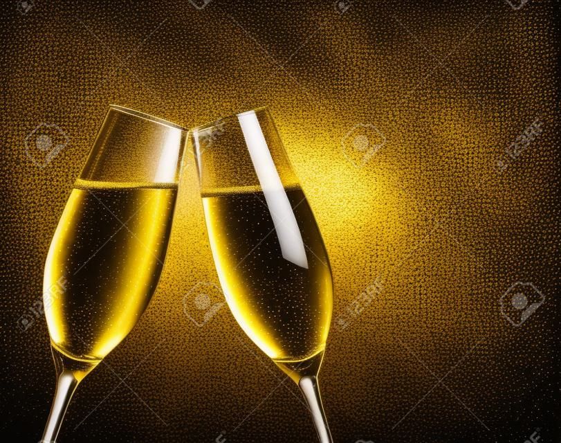 two champagne flutes with golden bubbles make cheers on black background with space for text