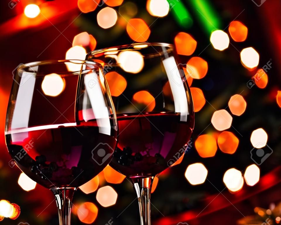 two red wine glass against christmas lights decoration background, christmas atmosphere