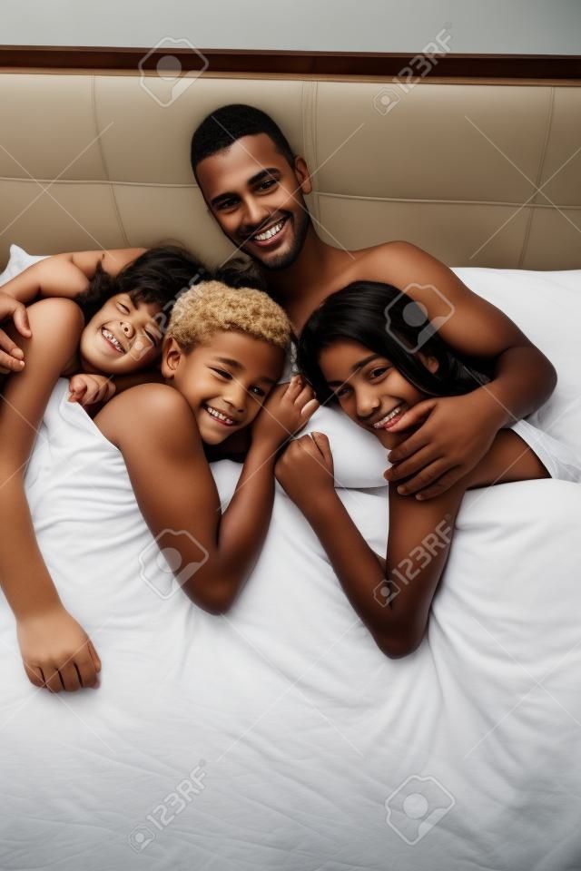 Jeune homme beau succès au lit avec trois filles de sommeil