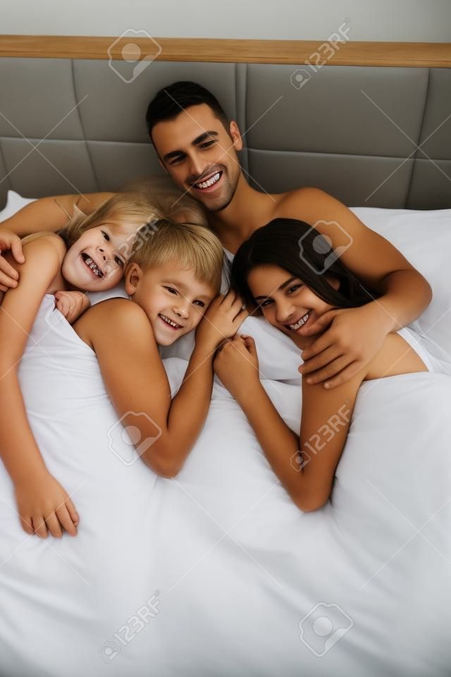 exitoso hombre guapo joven tumbado en la cama con tres chicas para dormir