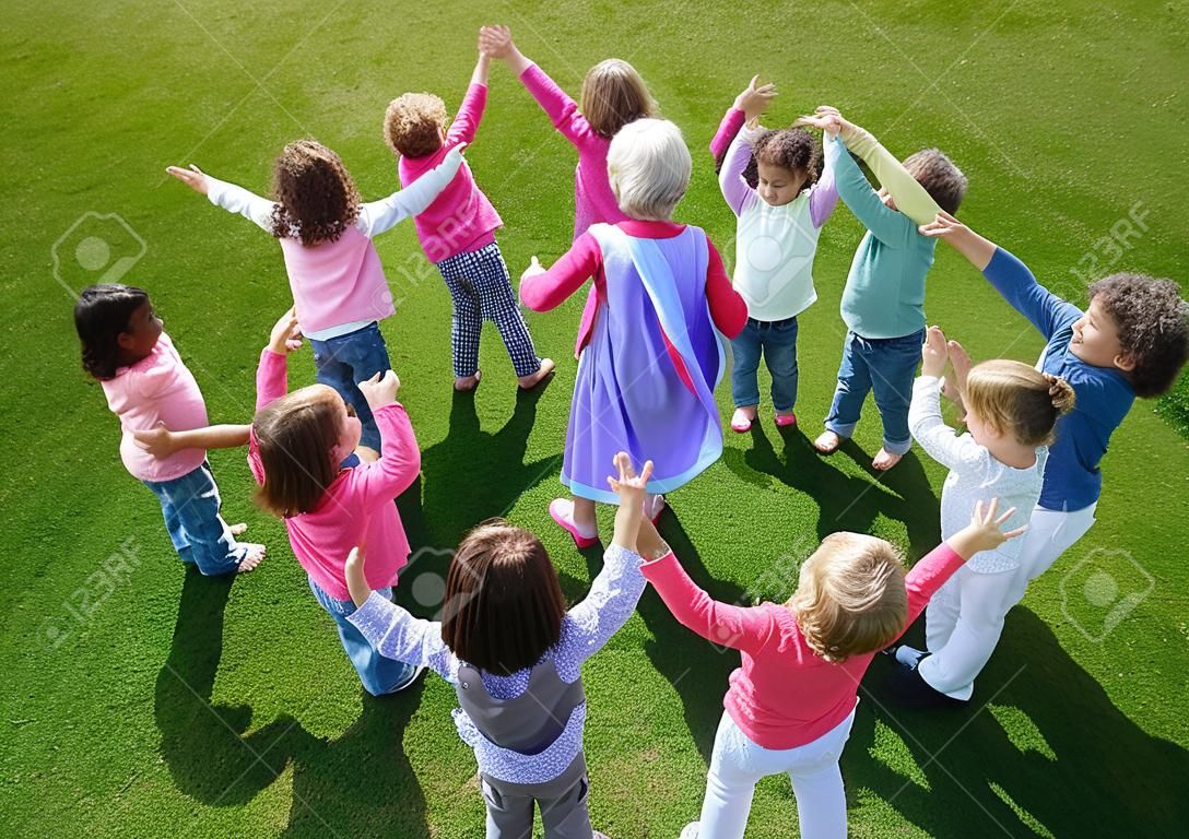 gelukkig kind kinderen groep hebben plezier en spelen op kleutertuin outdoor kleuterschool onderwijs concept met leraar